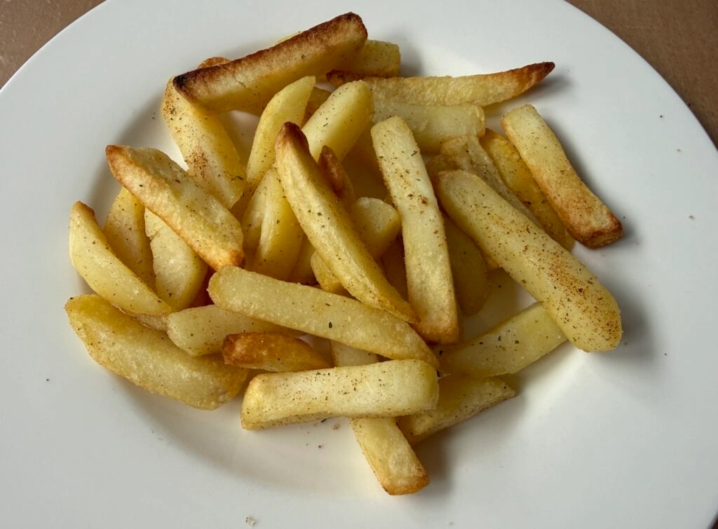 Frittierte Pommes auf einem weißen Teller.