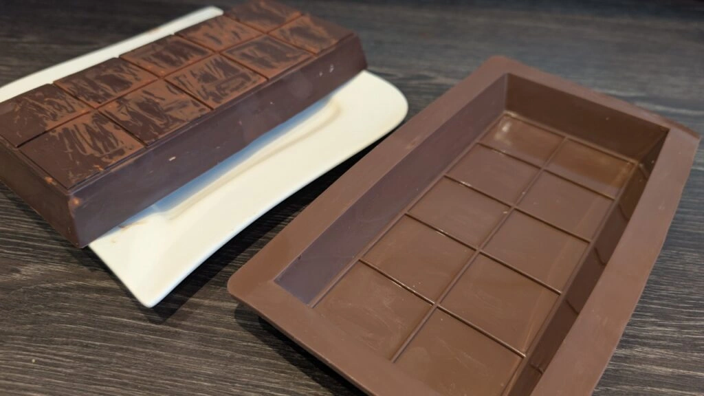 Silikonform und fertig herausgelöste Schokoladentafel nebeneinander.