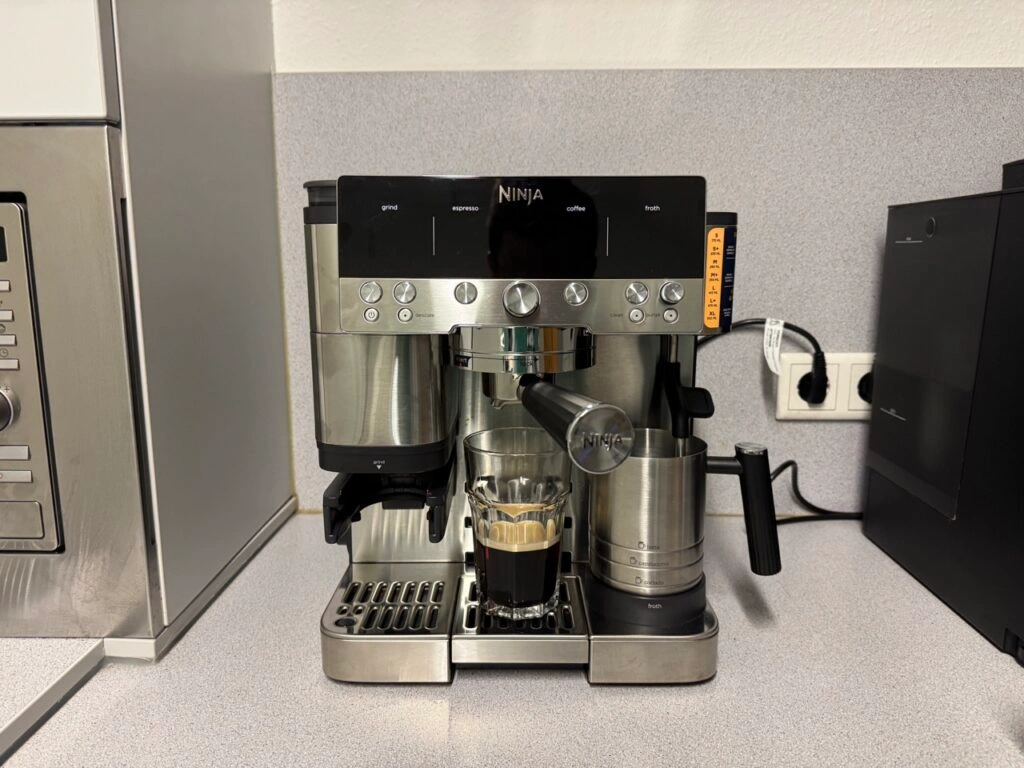 Ninja-Kaffeemaschine nach der Espressozubereitung mit eingesetztem Glas und Milchkaraffe.