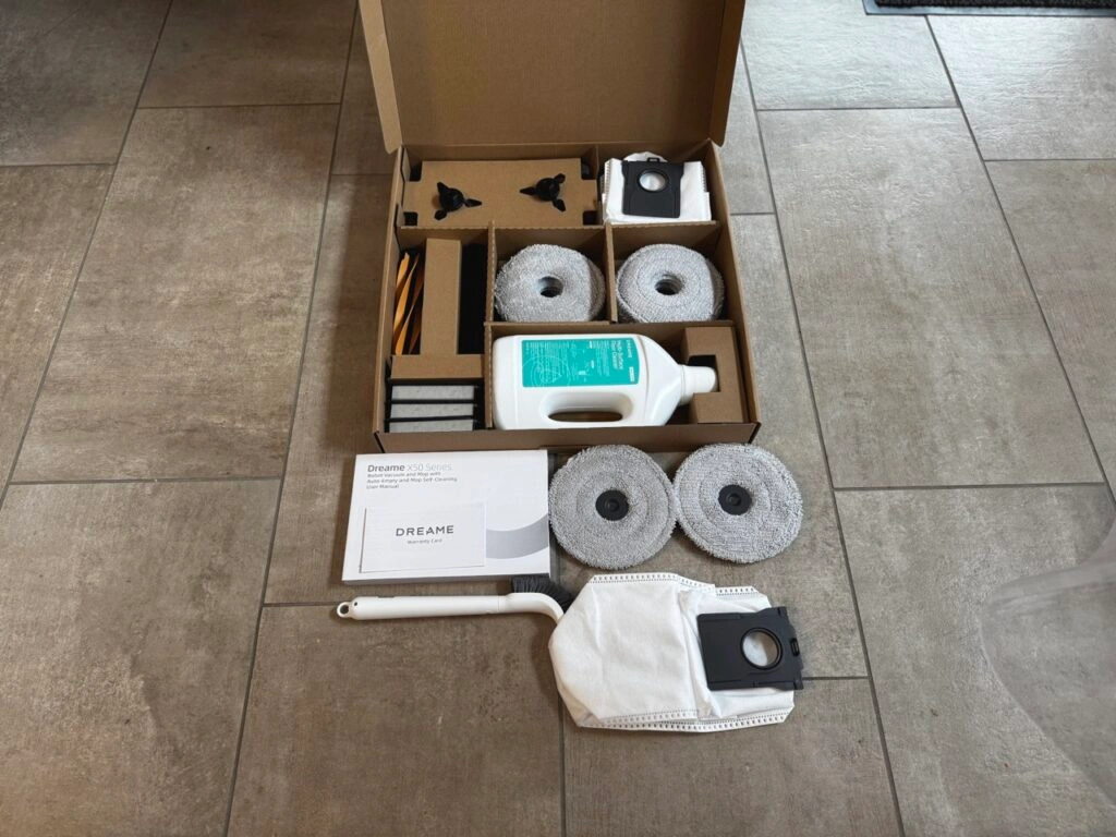 Gesamtaufnahme des Zubehörumfangs inklusive 12 Wischpads, drei HEPA-Filter, Saugbeutel, eine Flasche Reinigungsmittel, zwei Seitenbürsten sowie zwei Saugbürsten (Foto: Testsieger.de)