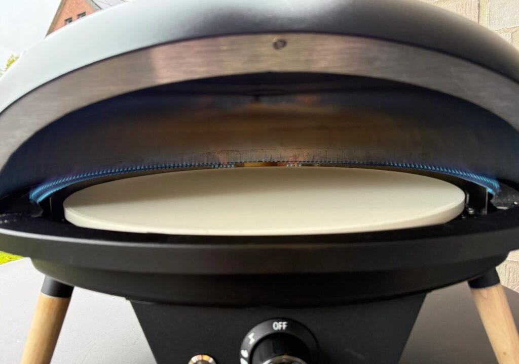 Blick in den aufgeheizten Le Feu Turtle Motion Pizzaofen mit sichtbarer Gasflamme und Pizzastein.