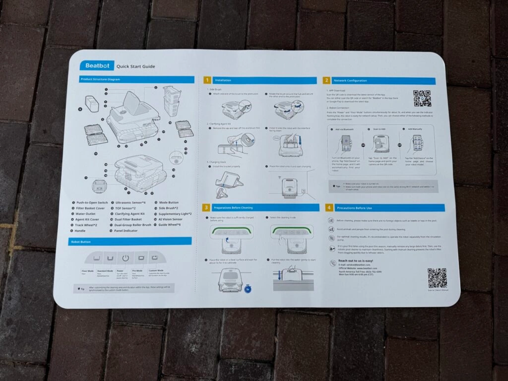 Ein großformatiges, bebildertes Poster zeigt die Schnellstartanleitung des Beatbot AquaSense 2 Ultra. Es ist auf einem Pflasterboden ausgebreitet. Zu sehen sind technische Zeichnungen des Roboters, eine nummerierte Schritt-für-Schritt-Erklärung zur Einrichtung, Hinweise zur App-Anbindung, zur Inbetriebnahme und zu Sicherheitshinweisen – alles ausschließlich in englischer Sprache.