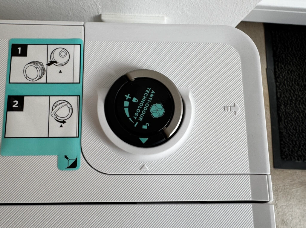 Nahaufnahme des Anti-Odour-Systems der Reinigungsstation des Shark PowerDetect NeverTouch Pro. Die Einstellungsmöglichkeiten für die Geruchsneutralisierung sind sichtbar, ebenso wie eine Anleitung zur Entnahme und Einstellung des Duftfilters.