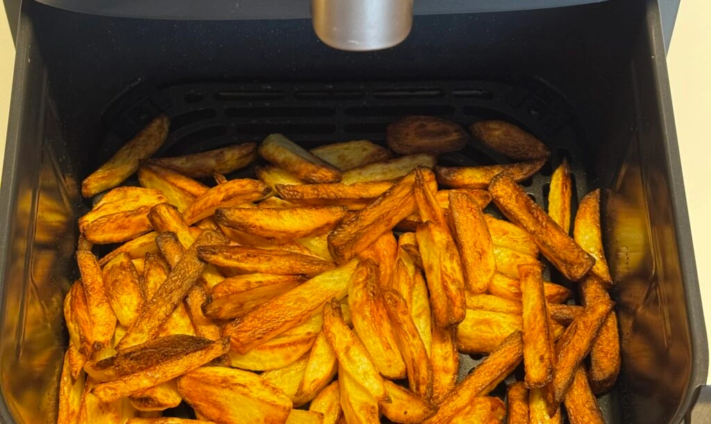 Nahaufnahme der selbstgemachten Pommes aus frischen Kartoffeln; alle Stäbchen sind sehr gleichmäßig gegart.