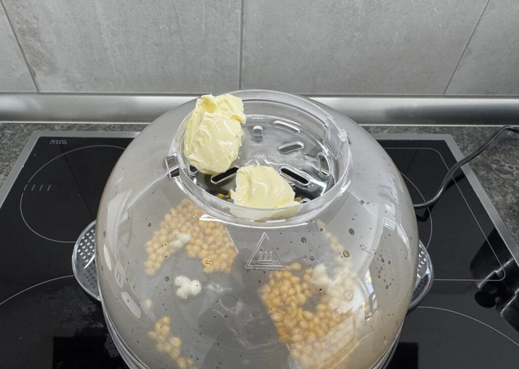 Princess 292980 Popcornmaschine: Maiskörner in der Kuppel mit Butteraufsatz