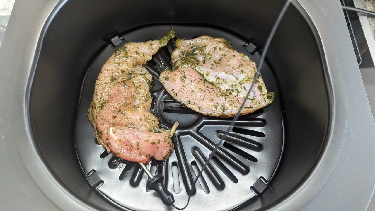 Nahaufnahme des Garkorbs, in dem das integrierte Thermometer sowie zwei Hähnchenbrustfilets befinden