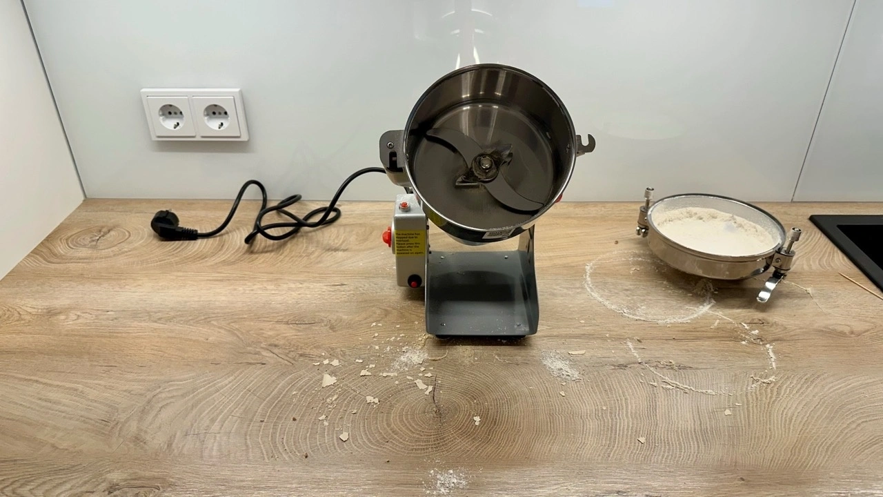 VEVOR Elektrische Getreidemühle HC-1000Y: Geöffneter Mahlbehälter und Mehlreste auf der Arbeitsfläche